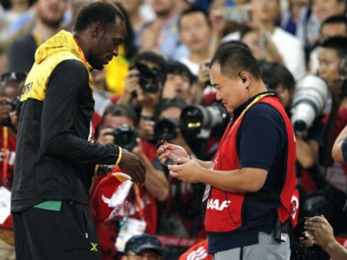 Bolt sa smiješkom prihvatio dar od kamermana koji mu je 'uklizao' tijekom slavlja